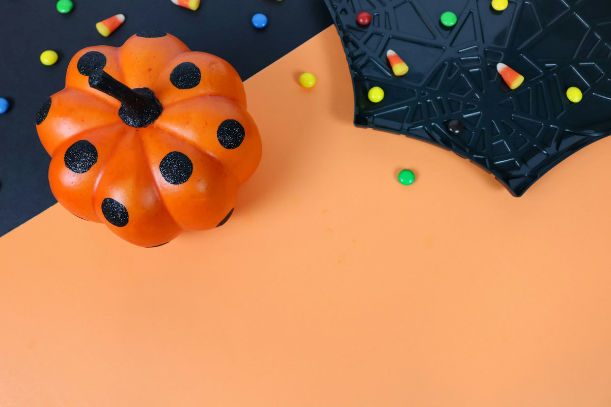 Halloween sweets, pumpkin and spiderweb plate on orange and black